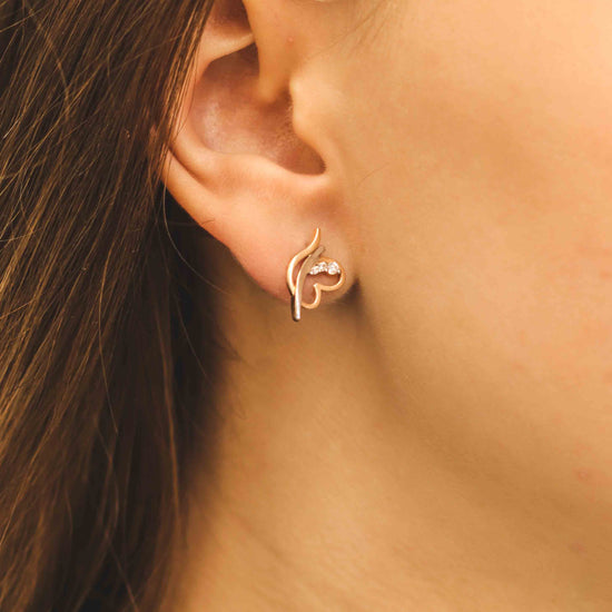 Rozā zelta dekoratīvs auskars ar dimanta akcentu — uz auss nēsāts skats