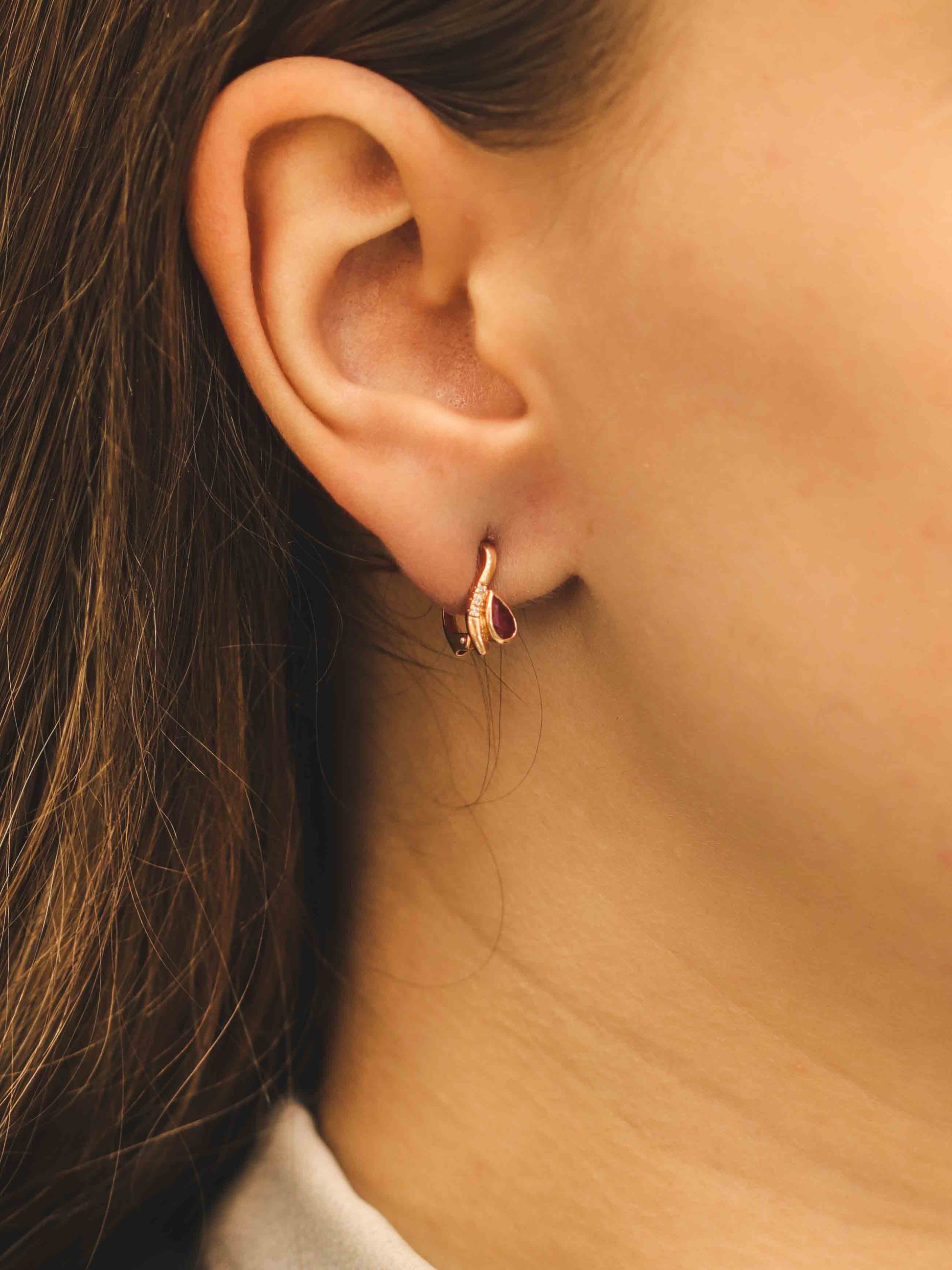 Auksiniai auskarai su rubinu ant ausies iš šono