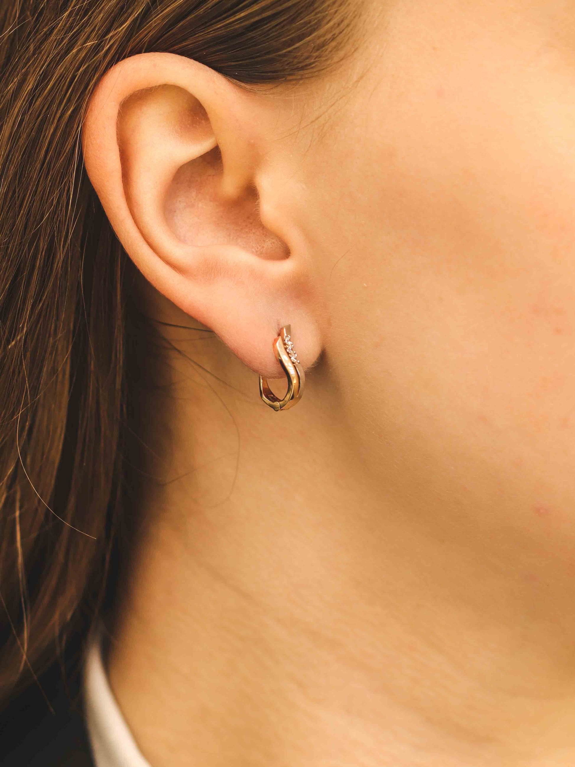 Eleganti viļņoti auskari rožu zeltā — modelim tuvplānā