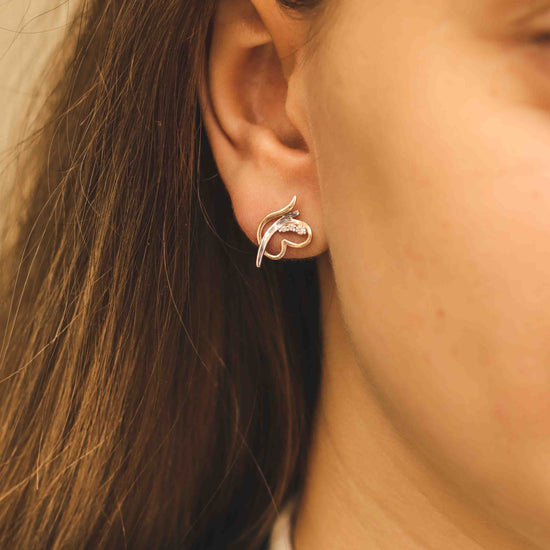 Elegants ornamentāls rožu zelta auskars — modelei tuvplānā