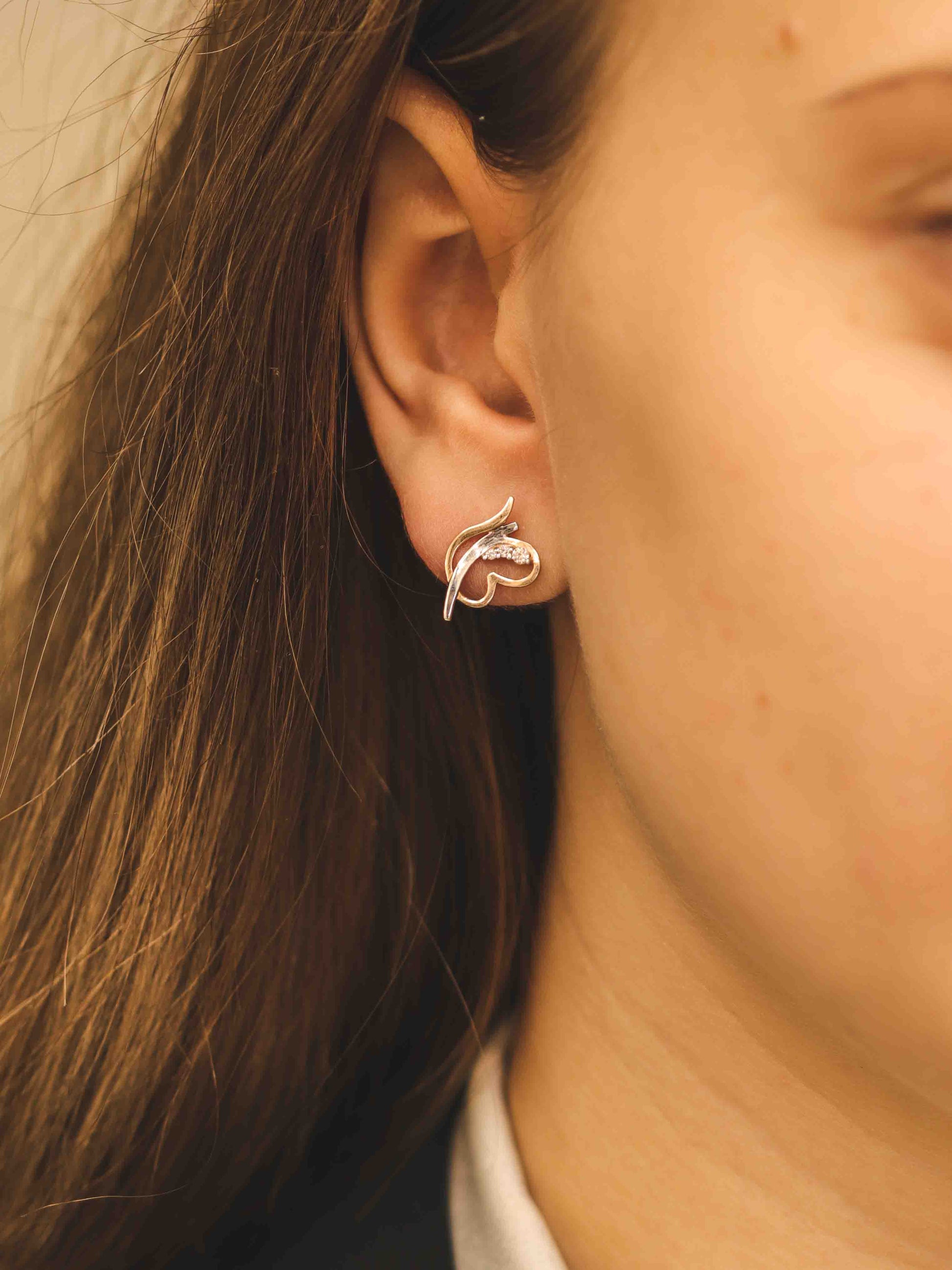 Elegants ornamentāls rožu zelta auskars — modelei tuvplānā