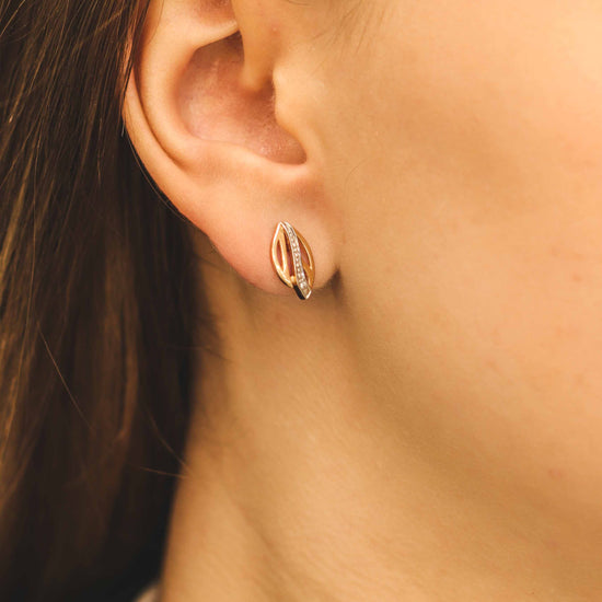 Eleganti rožu zelta auskari — modelei tuvplānā