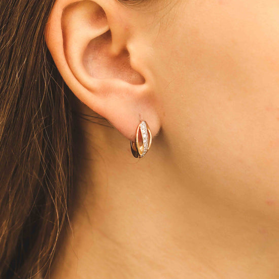 Eleganti rožu zelta auskari ar modernu formu - tuvplānā uz modeli