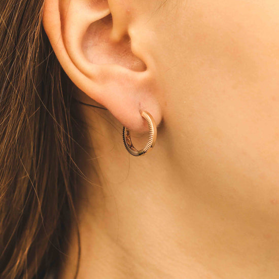 Elegants tekstūras rozā zelta stīpas auskars tuvplānā modelim