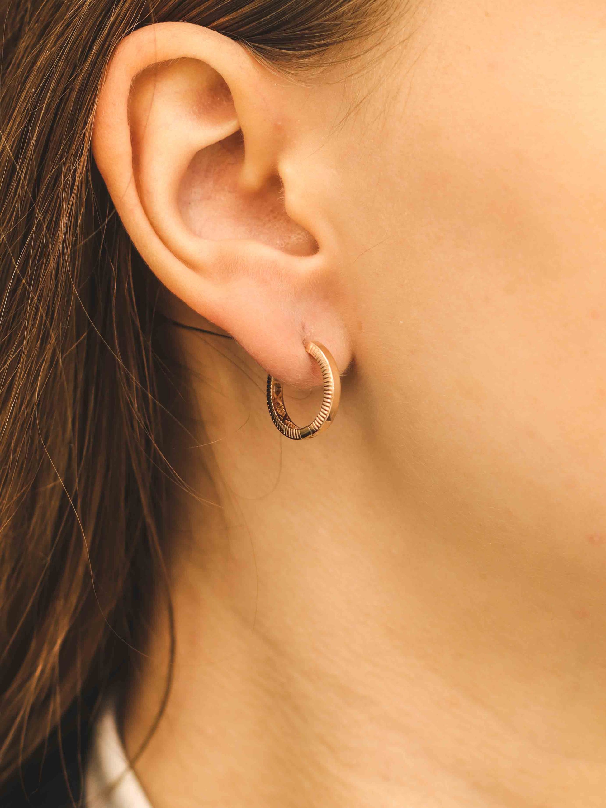 Elegants tekstūras rozā zelta stīpas auskars tuvplānā modelim