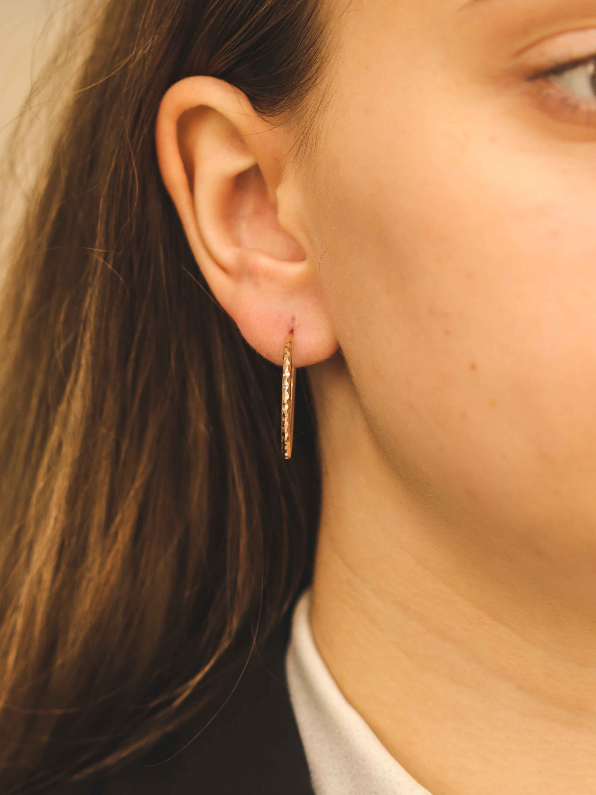 Plāns rozā zelta tekstūras stīpveida auskars uz modeļa