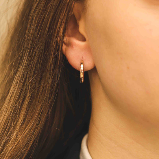 Elegants tekstūras rozā zelta stīpas auskars tuvplānā modelim