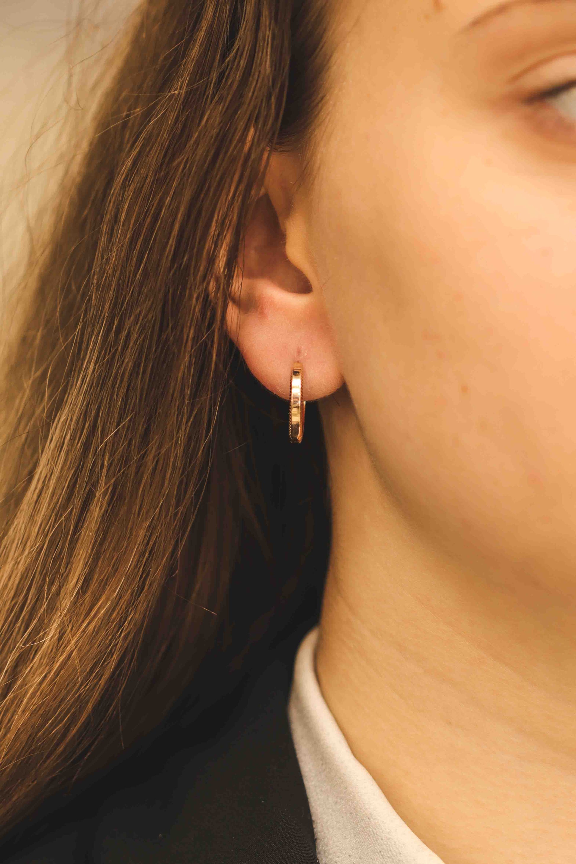 Elegants tekstūras rozā zelta stīpas auskars tuvplānā modelim