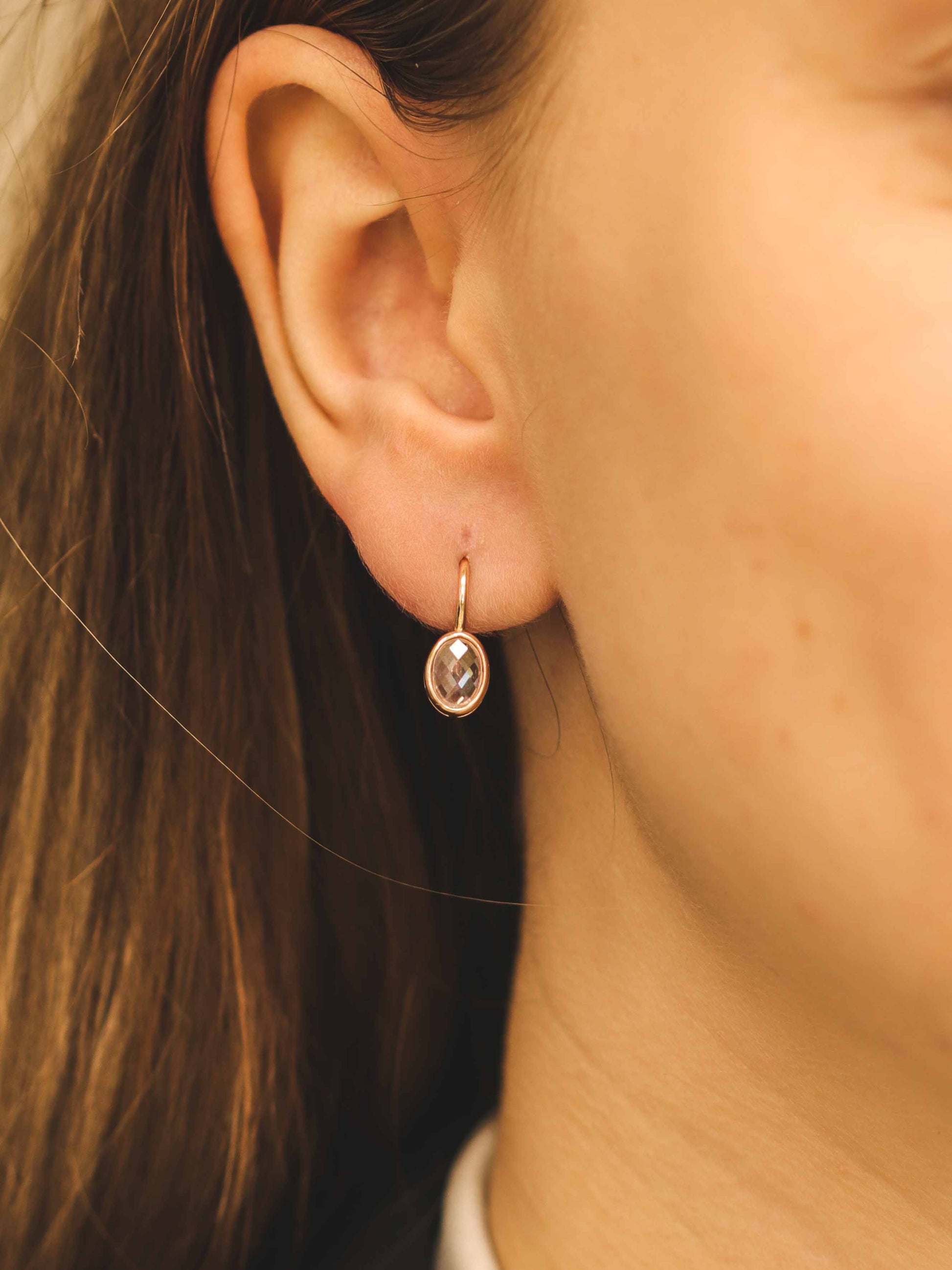 Elegantiški rožinio aukso auskarai su skaidriu akmeniu – dėvėjimo vaizdas iš arti