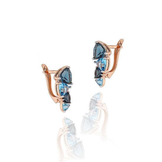 Elegantiški auskarai su mėlynos spalvos akmenų kompozicija – detalus fragmentas