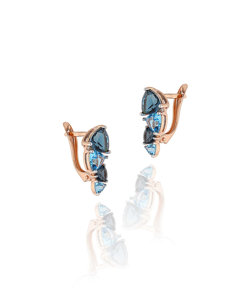 Elegantiški auskarai su mėlynos spalvos akmenų kompozicija – detalus fragmentas