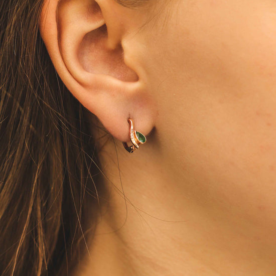 Moteris dėvi auskarus su smaragdu