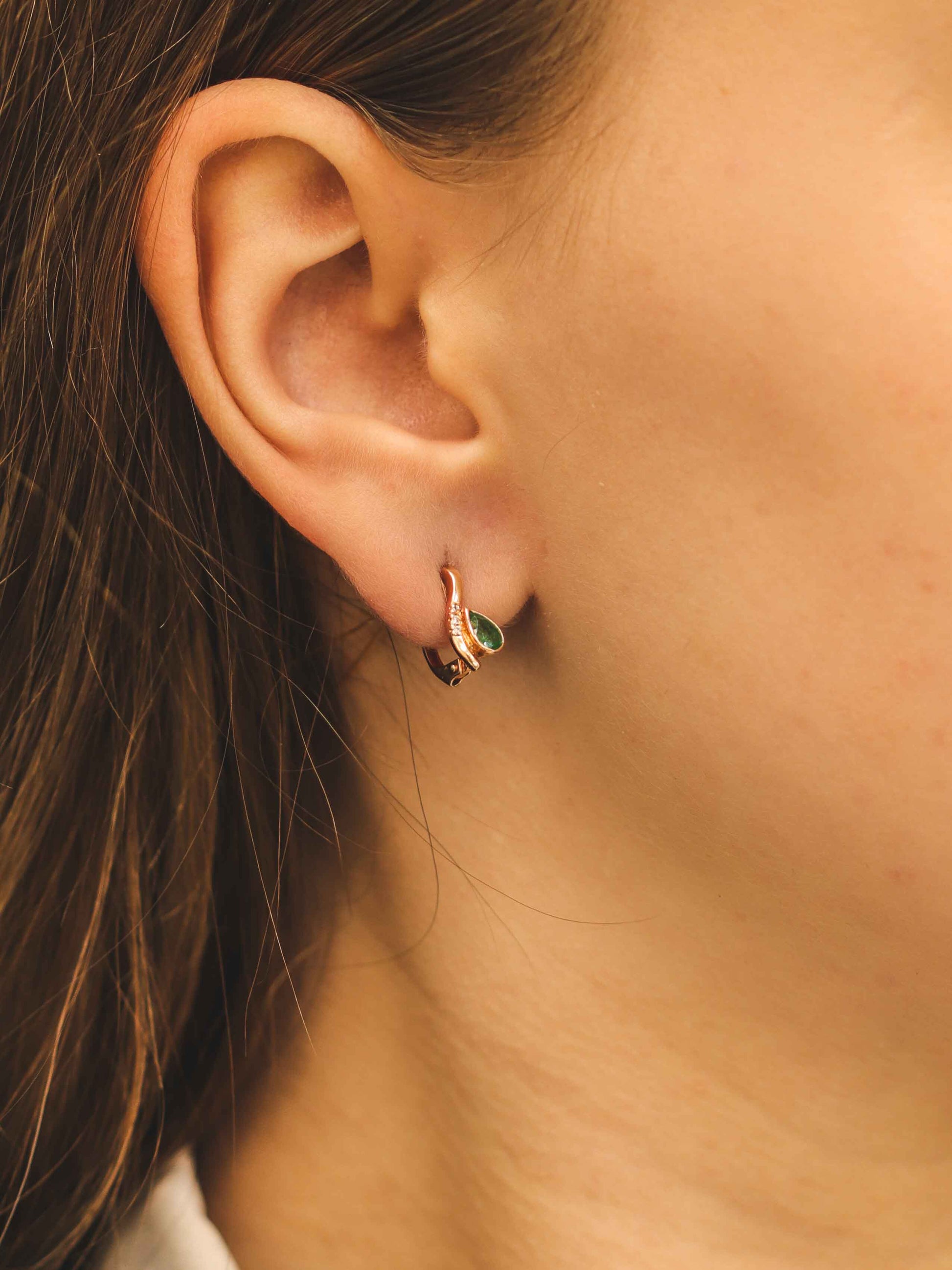 Moteris dėvi auskarus su smaragdu