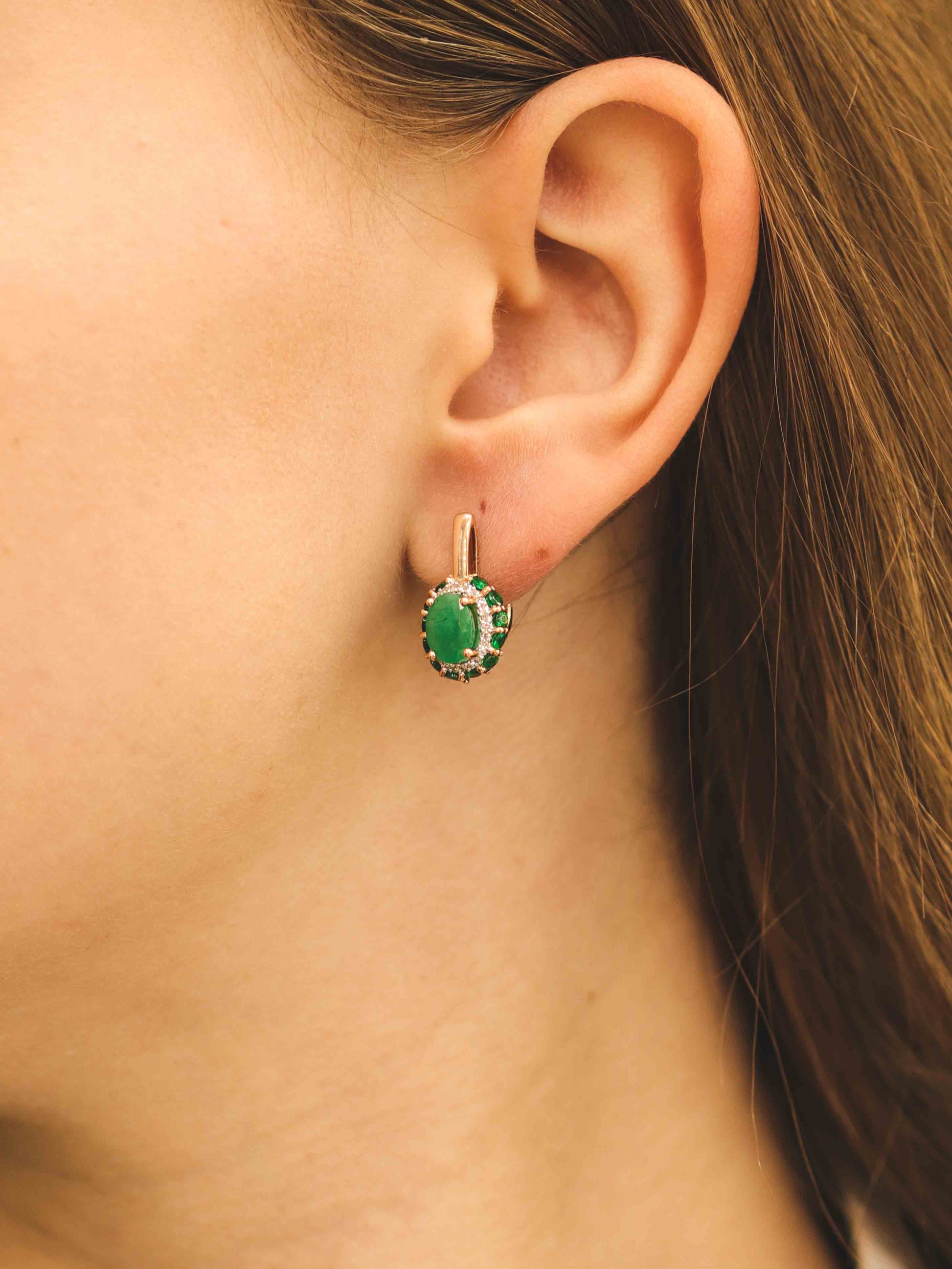 Moteris dėvi auskarus su ovaliu smaragdu