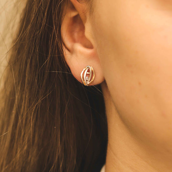 Dvispalviai auksiniai auskarai ant ausies