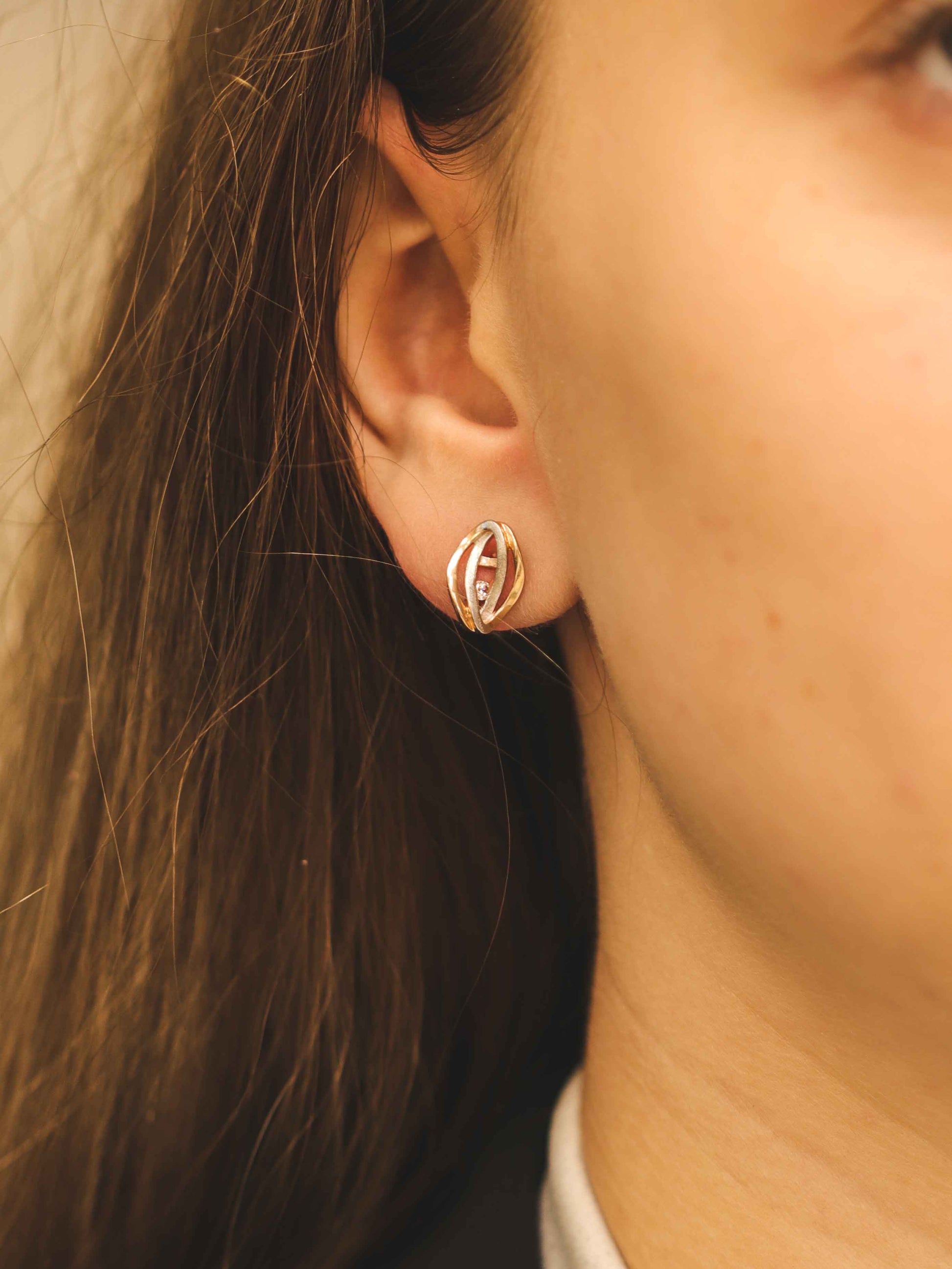 Dvispalviai auksiniai auskarai ant ausies