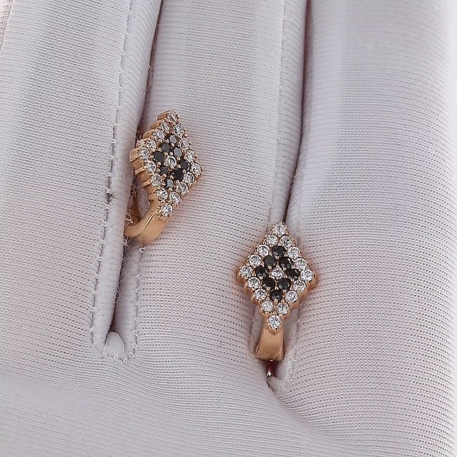 Auksiniai auskarai su juodais ir baltais cirkoniais – studijinė nuotrauka