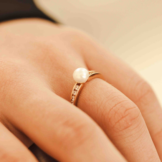 Žiedas su baltu perlu ir mažais deimantais ant rankos
