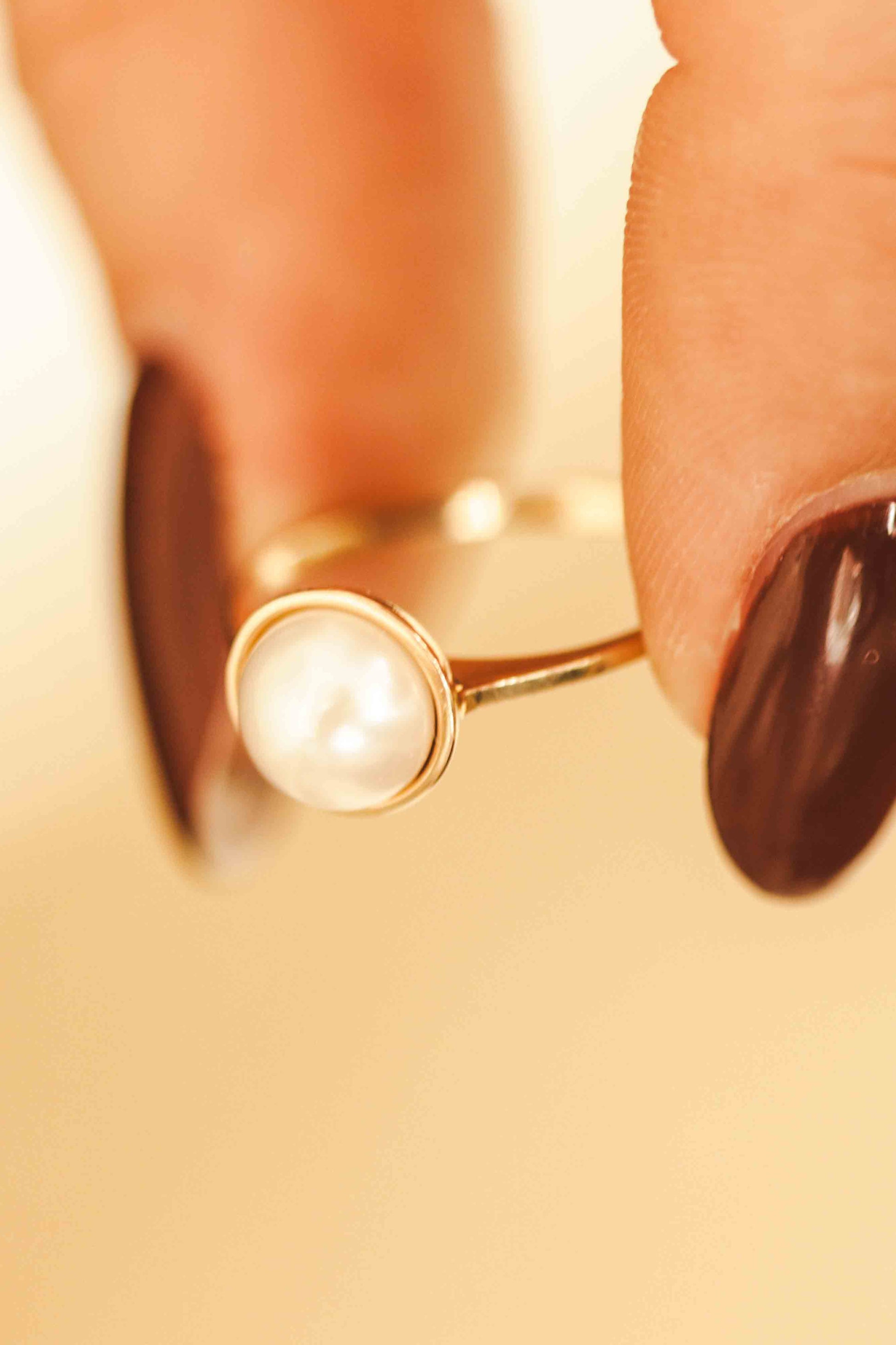 Elegantiškas auksinis žiedas su perlu dėvimas